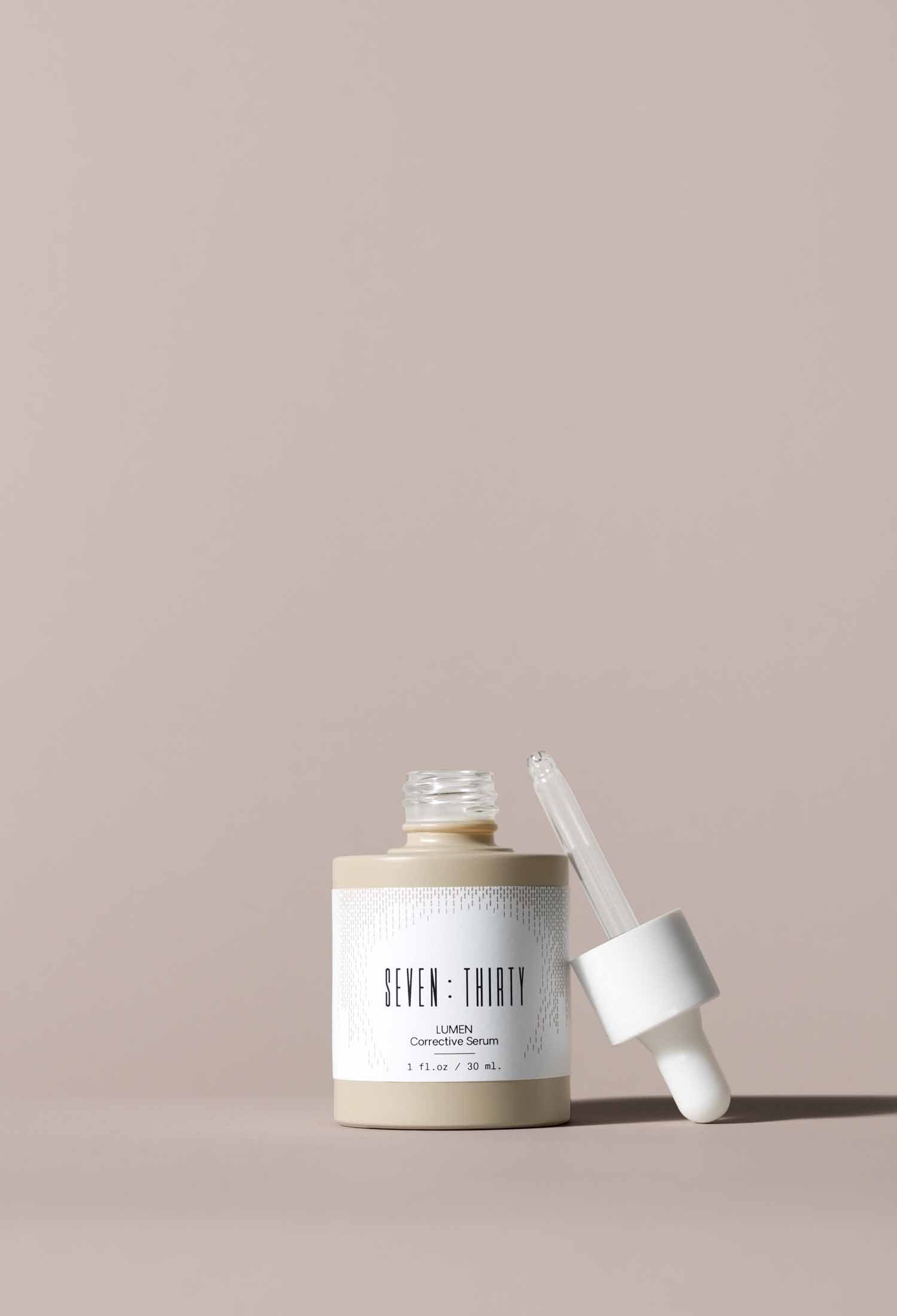 LUMEN Corrective Serum, with its dropper resting against the bottle, on a khaki background