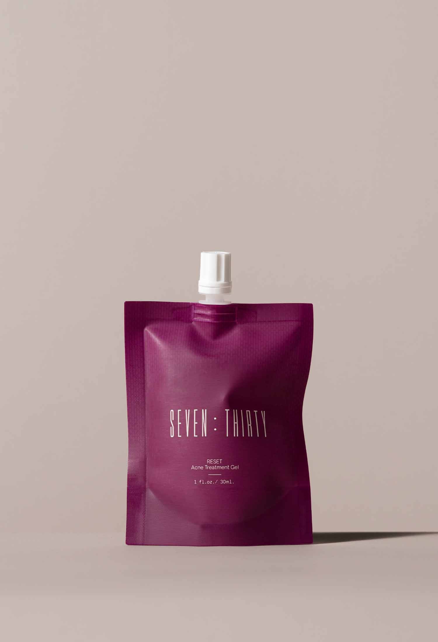 RESET Acne Gel Treatment in a dark cherry pouch on a khaki background