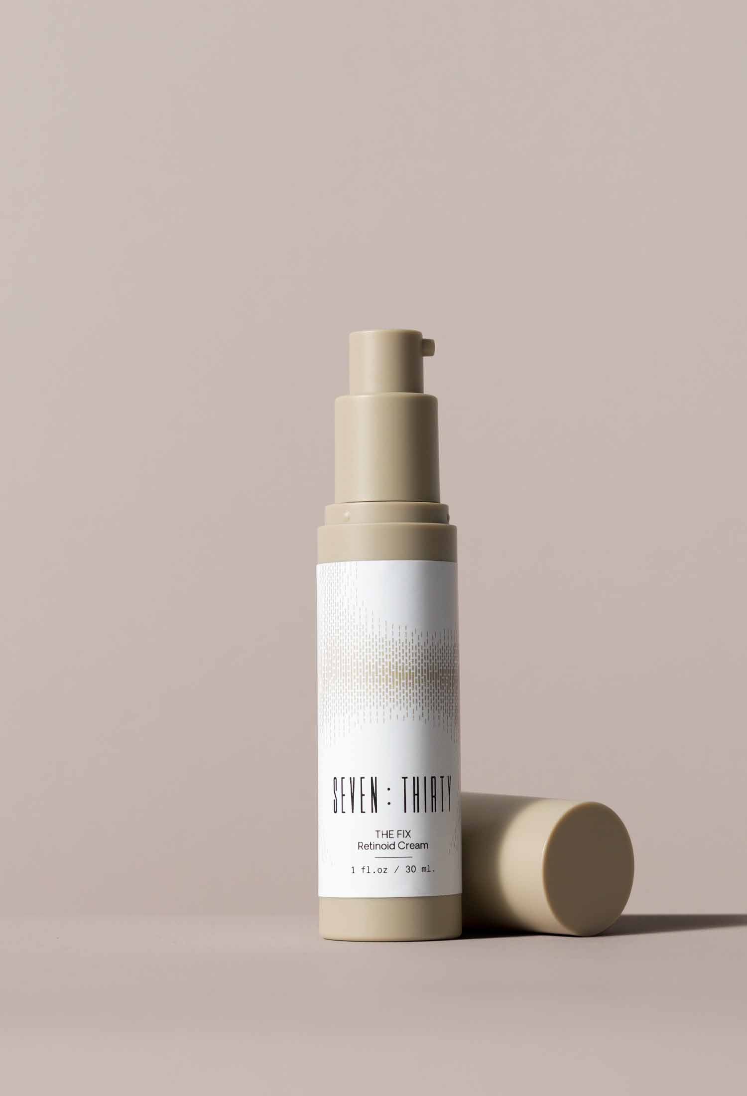 THE FIX Retinoid Cream, with its cap placed next to the bottle, on a khaki background 